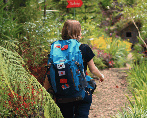 Photo représentant une backpackeuse en train de marcher avec son sac sur le dos 